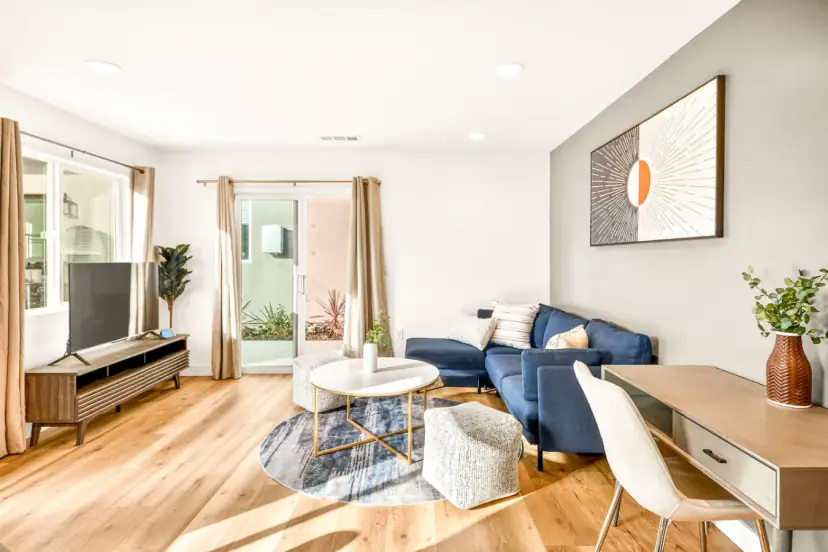 Second living room with a blue sectional and a desk by the window