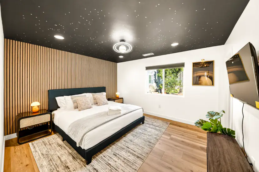 Bedroom with a starry black ceiling, a wood-slat wall and a king bed