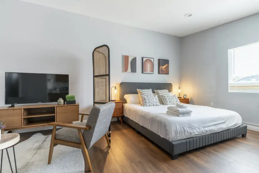 Bed with a TV console and a grey armchair