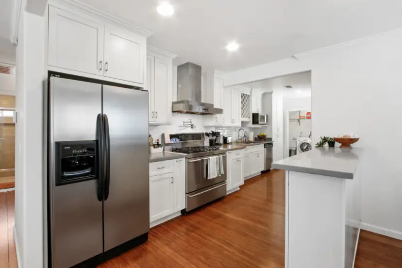 White kitchen with a stainless fridge and a gas range
