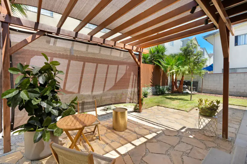 Shaded patio under a pergola with a bistro table and a lawn beyond