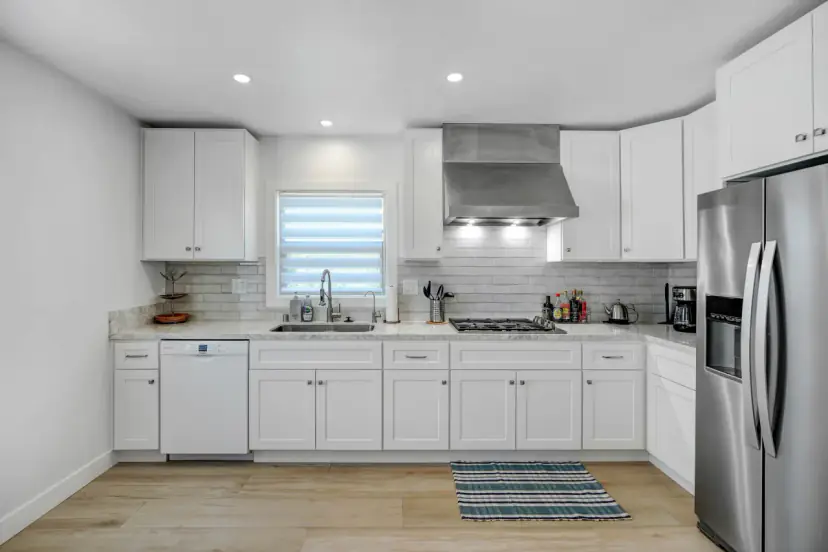 White kitchen with a stainless fridge and a range hood