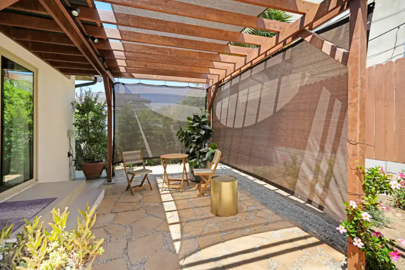 Stone patio under a pergola with shade cloth and folding chairs