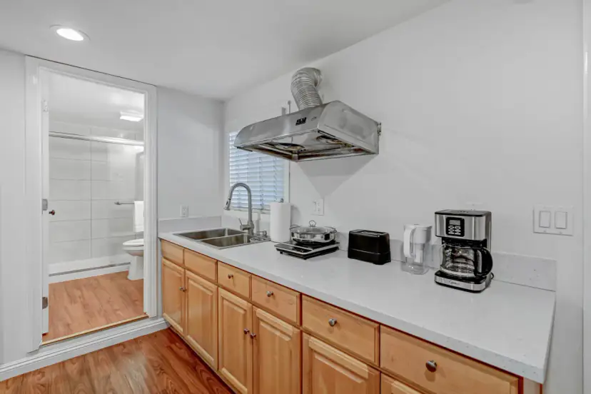 Kitchen with honey-wood cabinets and the bathroom beyond