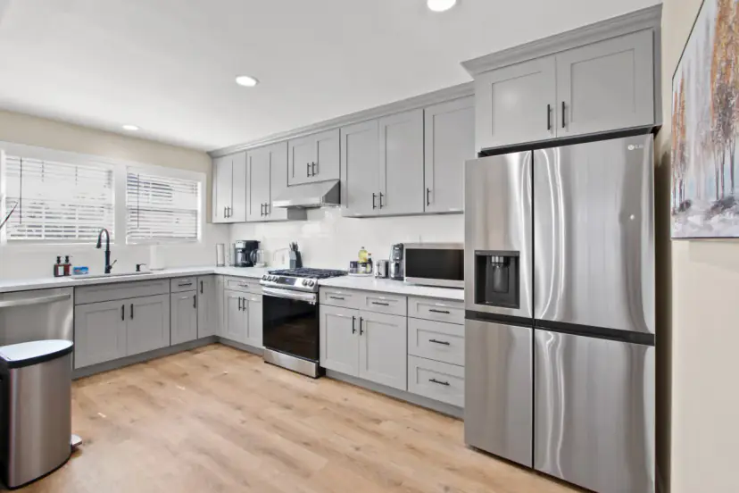 Grey shaker kitchen with a stainless fridge and a gas range