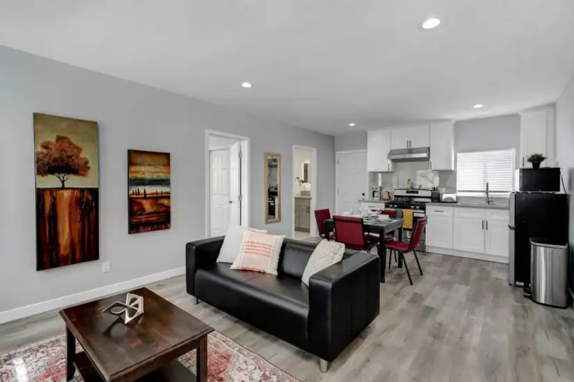 Living room with a black leather sofa and the kitchen beyond