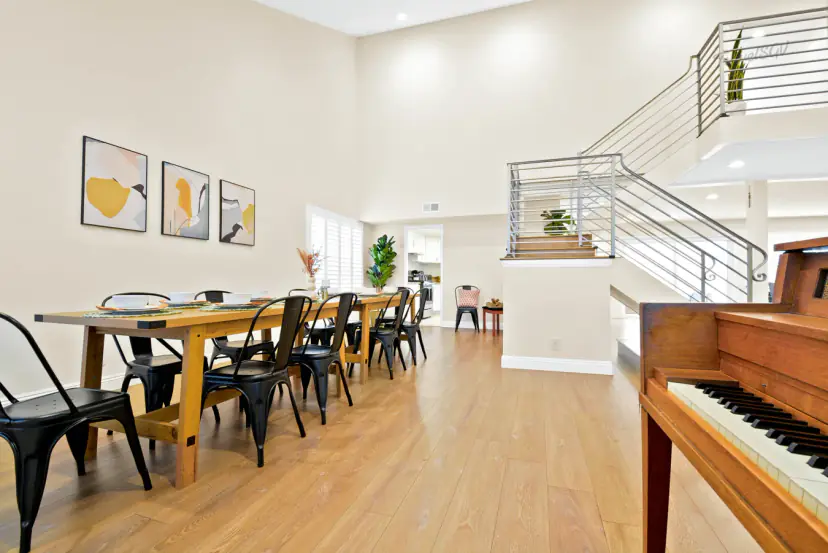 Long wooden table with twelve chairs beside an upright piano