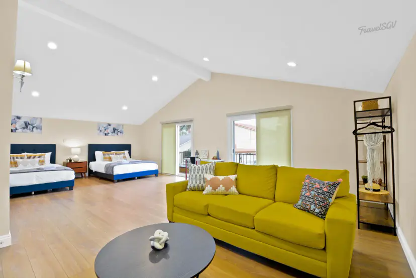 Open room with two beds and a chartreuse sofa