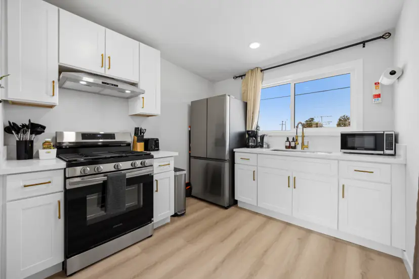 Upstairs white kitchen with a gas range and fridge