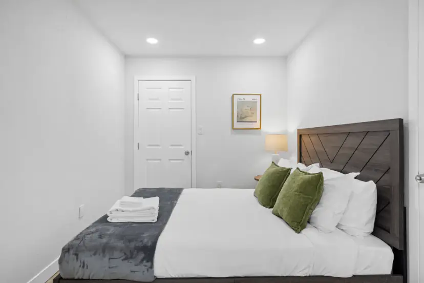Bed with a wood headboard and green pillows