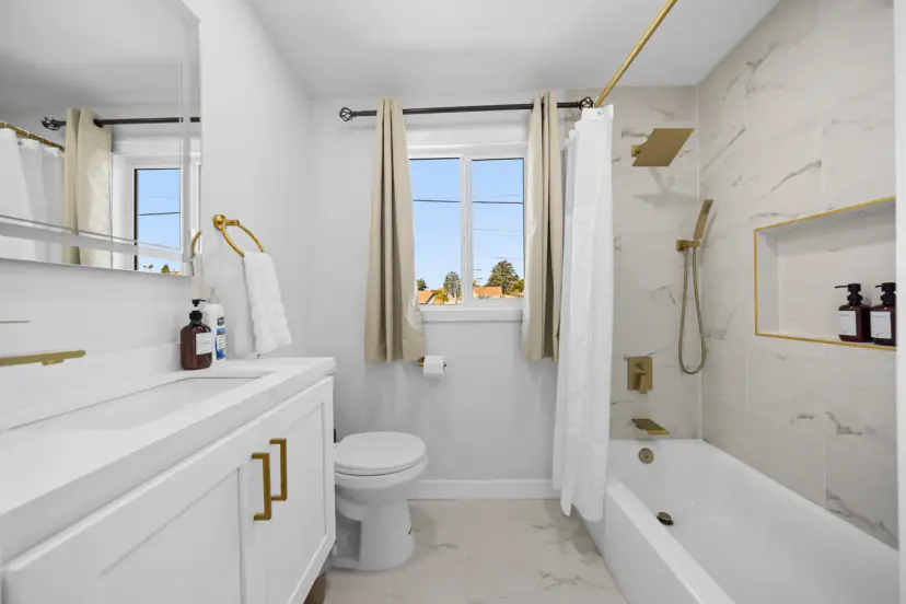 Bathroom with a tub, gold fixtures and window