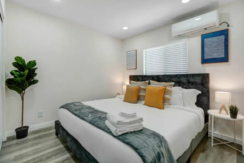 Bedroom with a king bed, mustard pillows and a fiddle-leaf fig