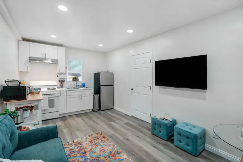 Living area with a wall TV and the kitchen beyond